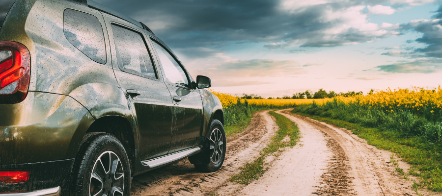 car on dirt road in field