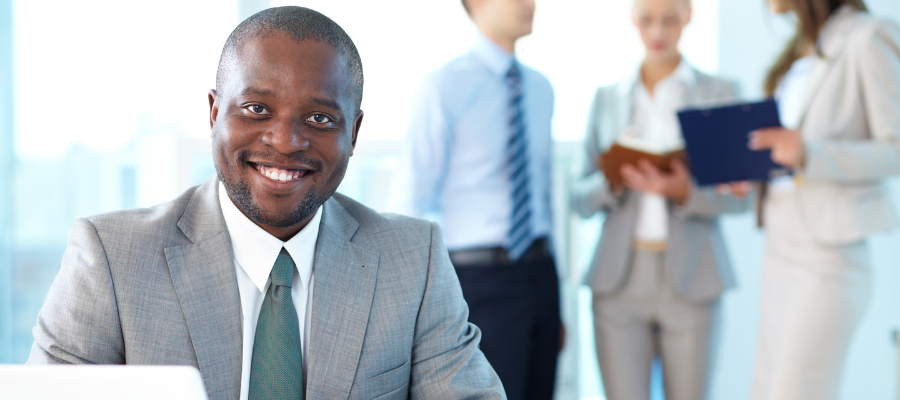 businessman behind desk with 3 coworkers in the background
